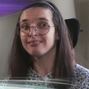 Person with long brown hair, glasses, and a slight smile, looking towards the viewer.