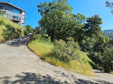 A road going up a hill with a house in the background.
