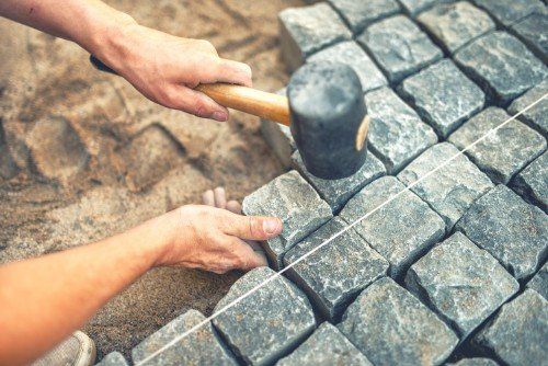 primo piano di mani che costruiscono un pavimento a mosaico in porfido