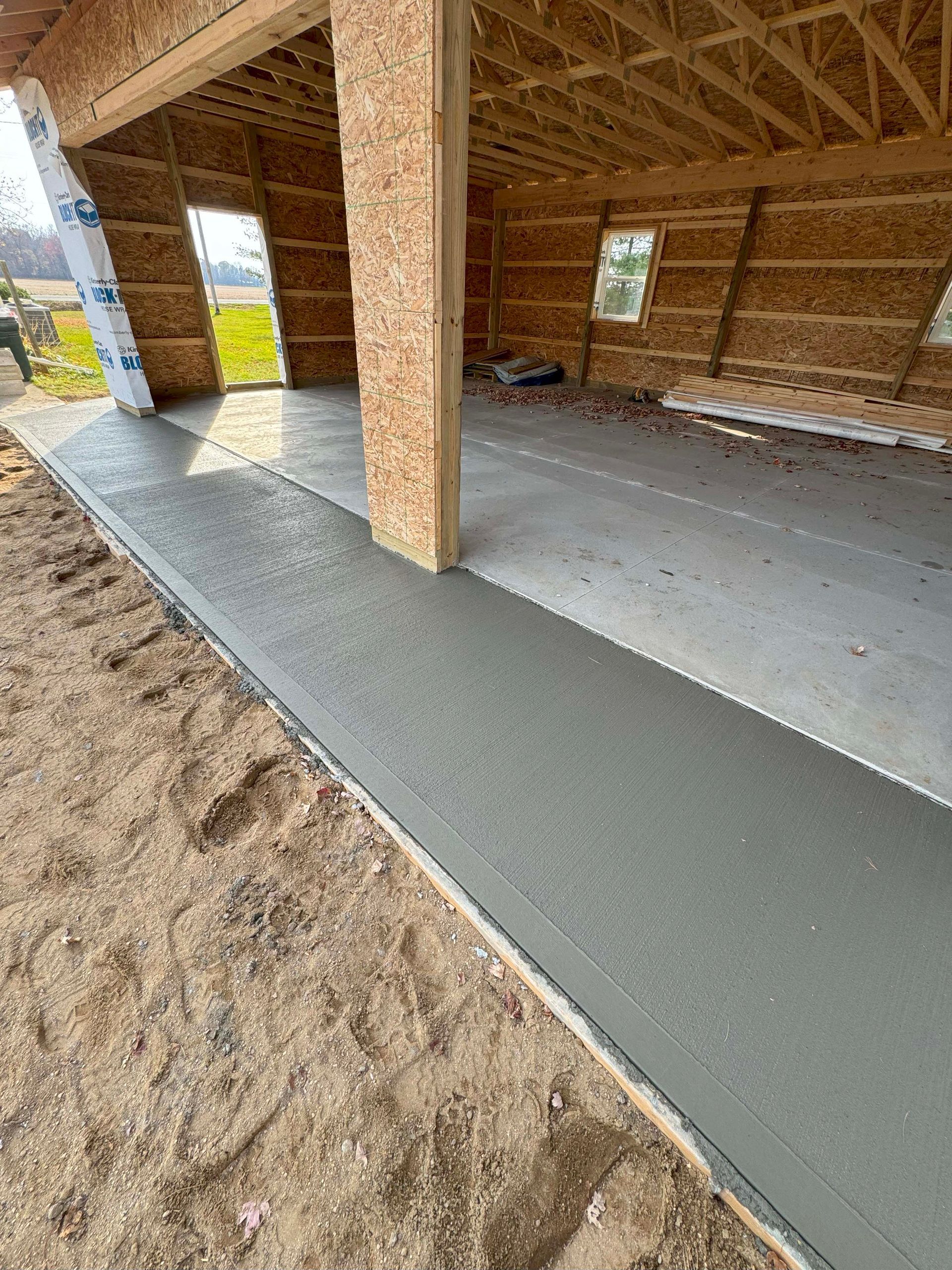 Newly poured concrete garage floor and sidewalk under construction, exterior view.