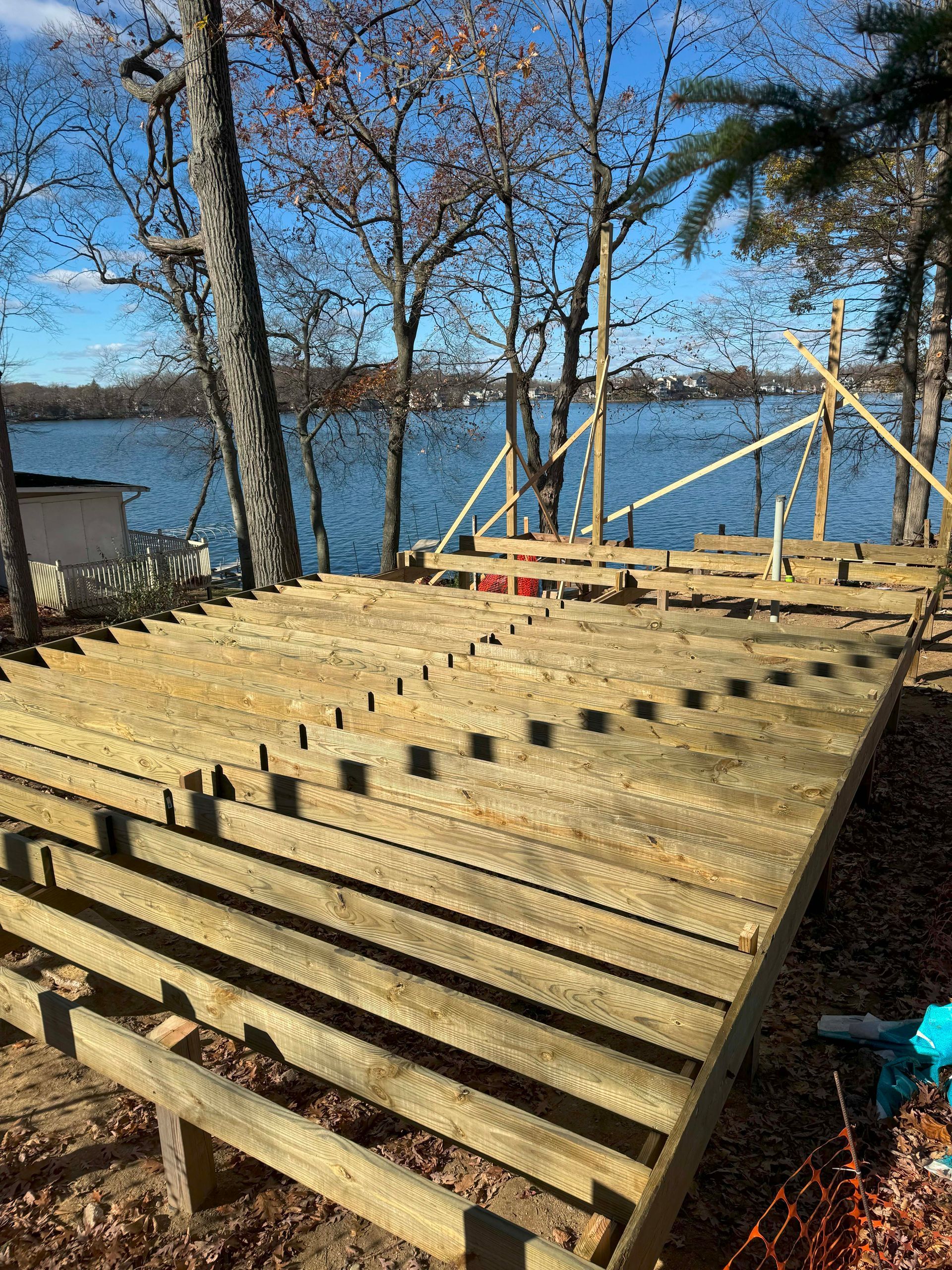 Construction site with wood deck frame overlooking a lake.
