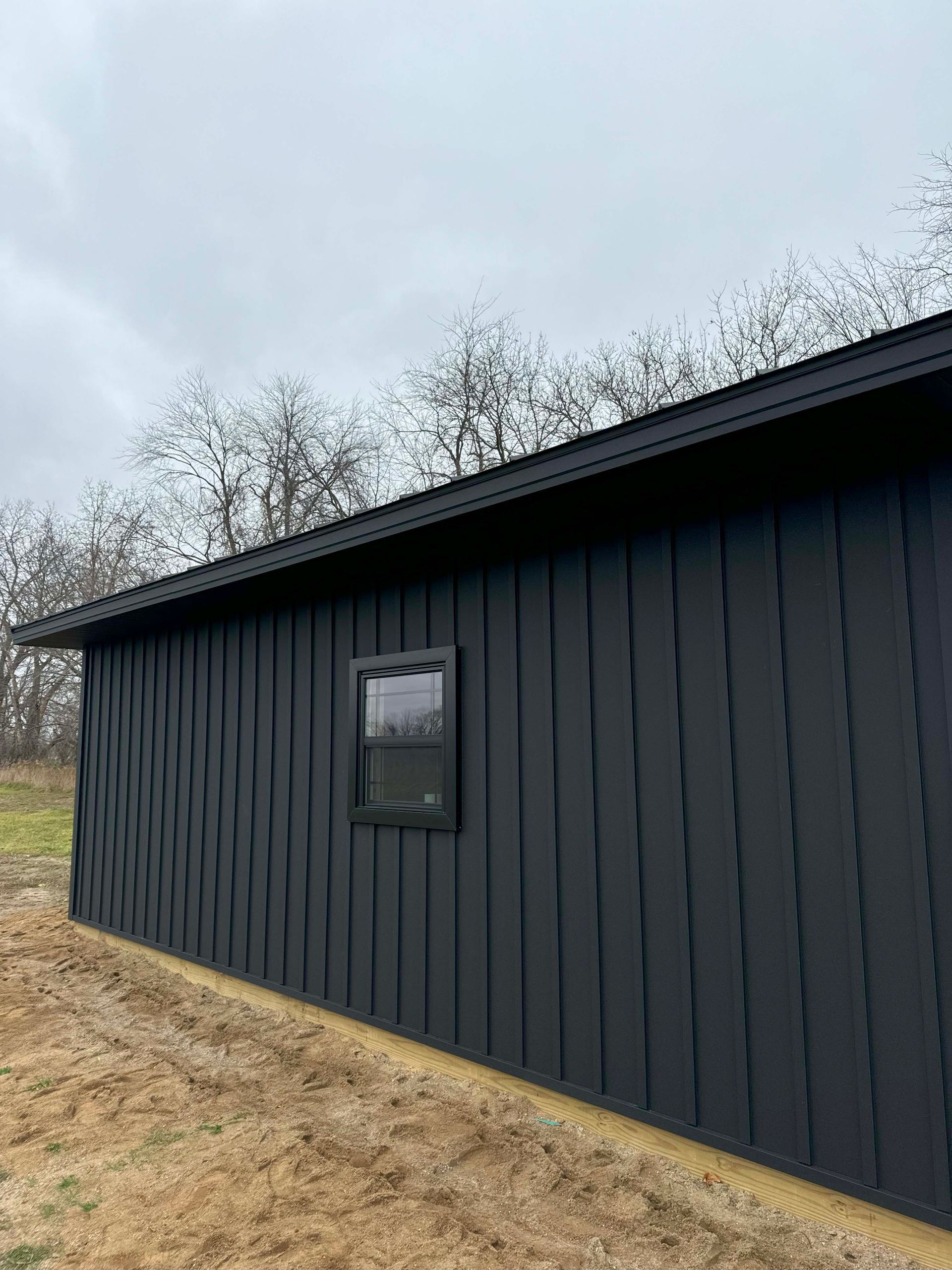 Black-sided building with a single window against a cloudy sky.