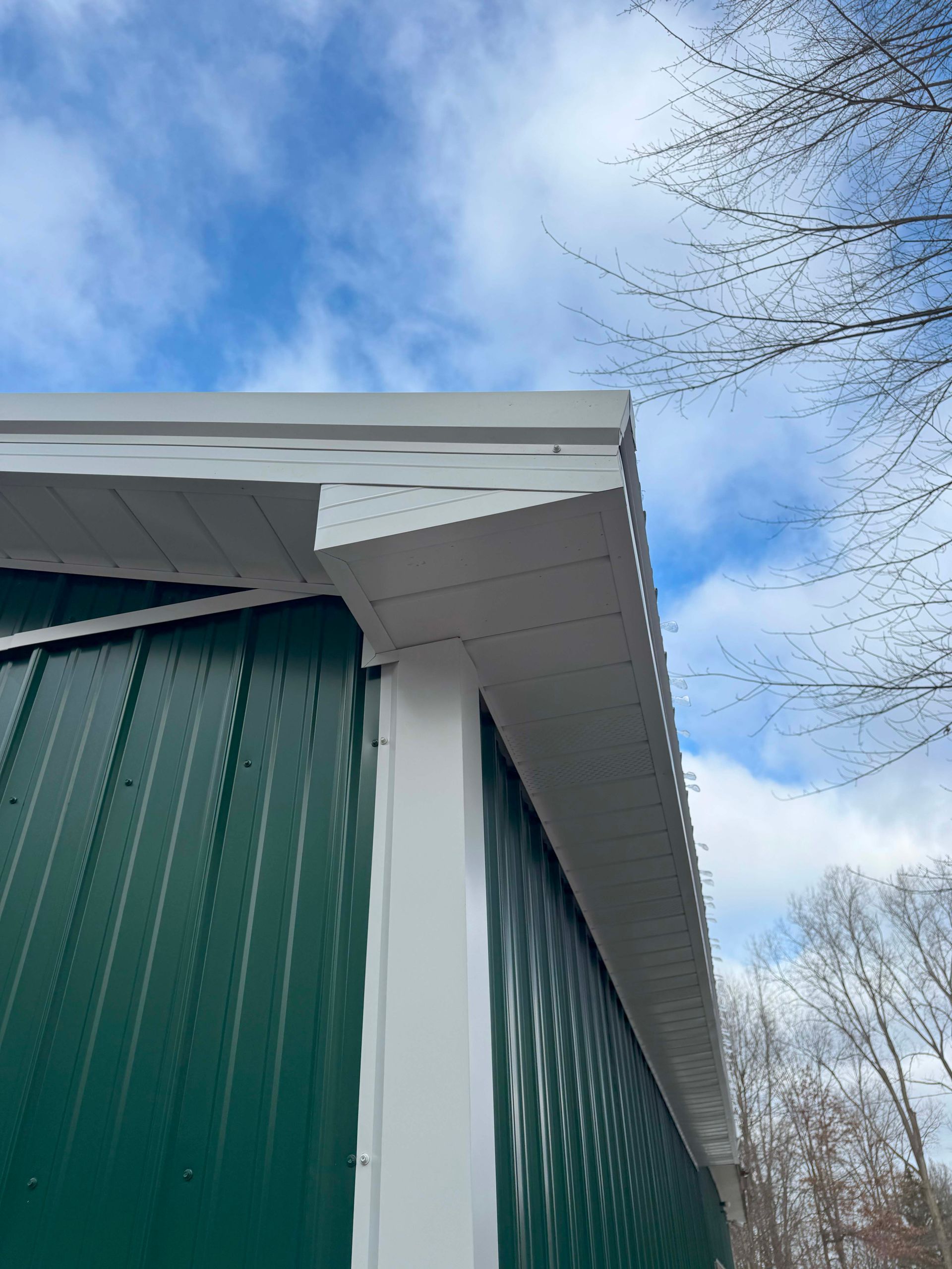 Green and white building corner against a cloudy sky.