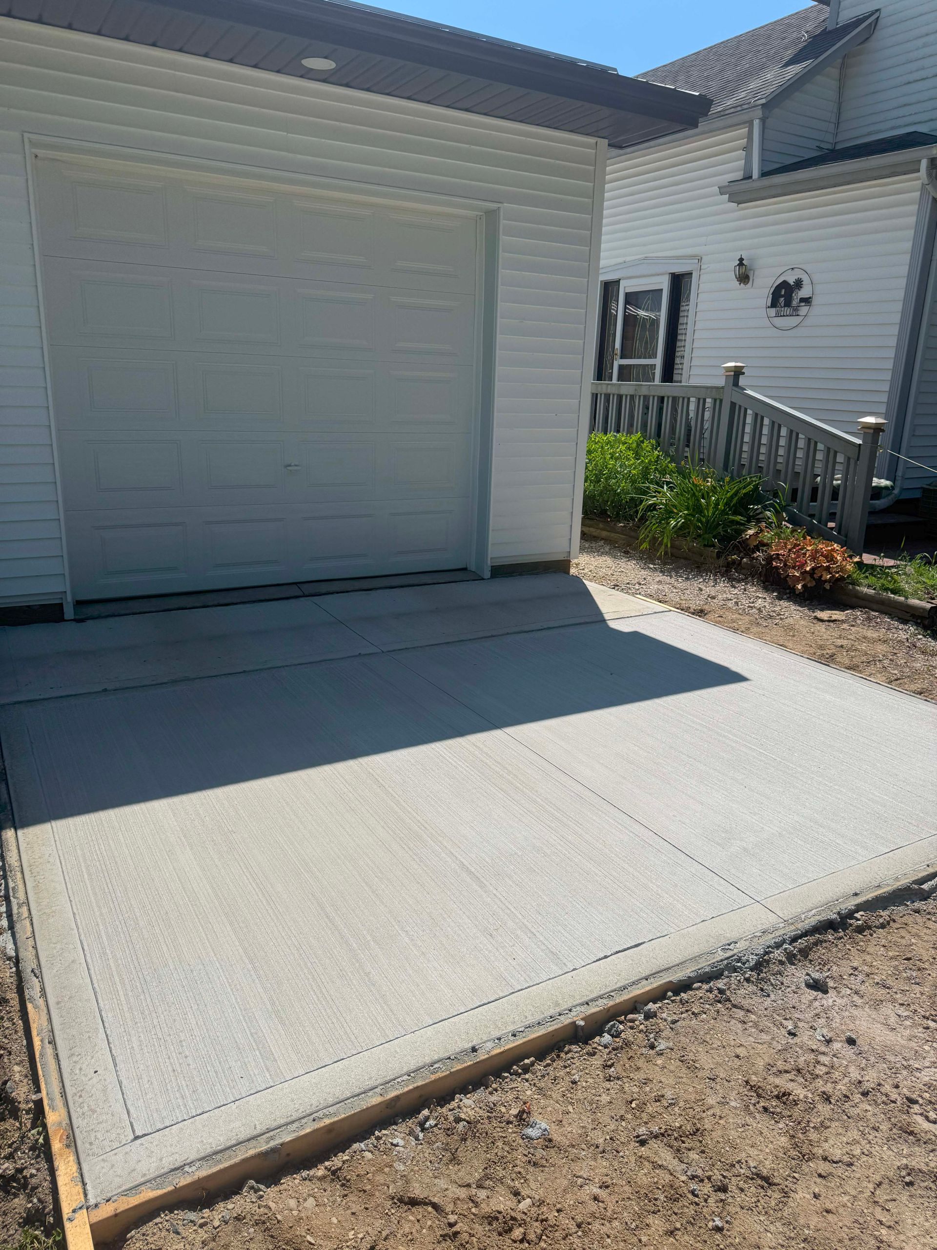 New concrete slab in front of a garage. Gray concrete, wooden border, sunny day.
