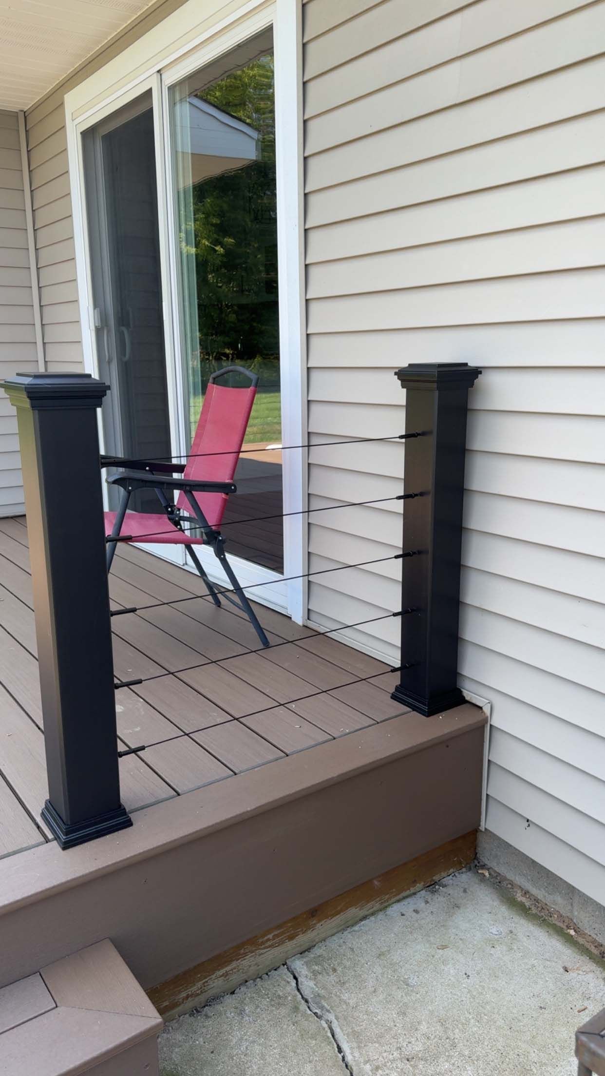 Black deck railing posts on a brown deck. A sliding glass door is in the background.