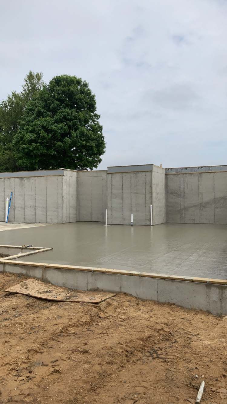 Concrete foundation walls with wet concrete floor; construction site.