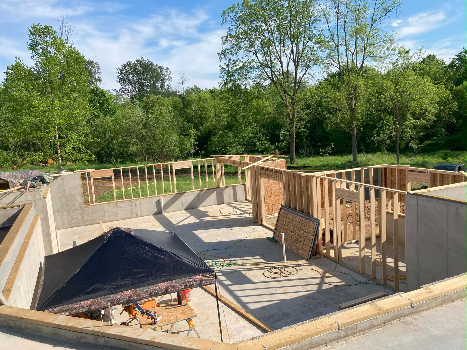 Construction site with concrete foundation and framed walls in a natural setting.