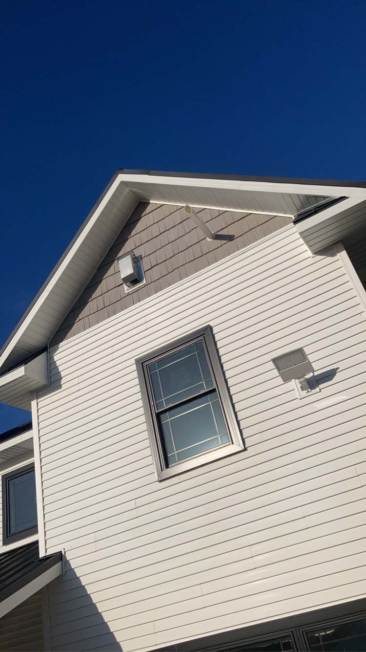 Exterior of a white house with a window, under a bright blue sky.