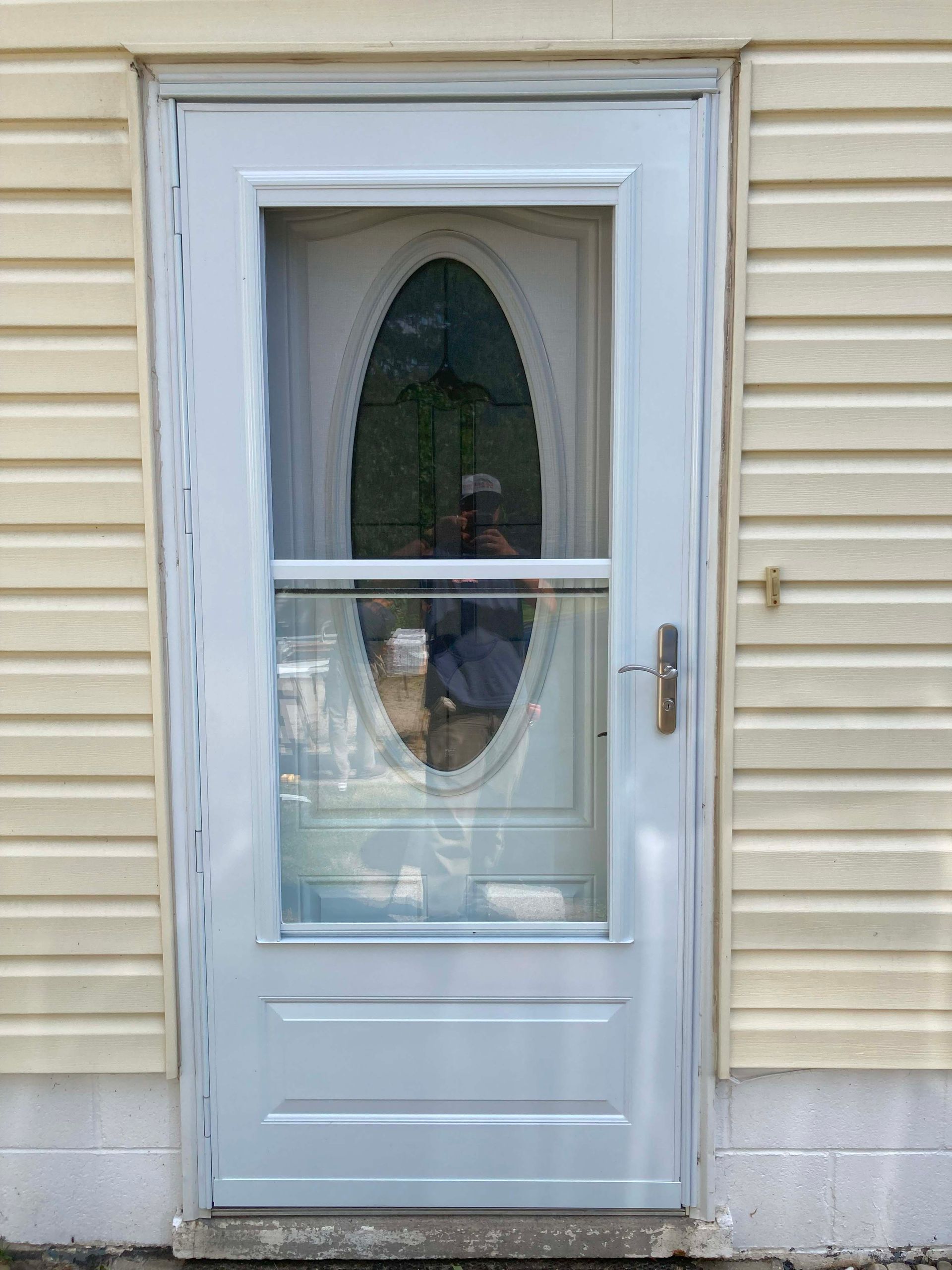 Light blue exterior door with oval glass panel, set in light yellow siding.