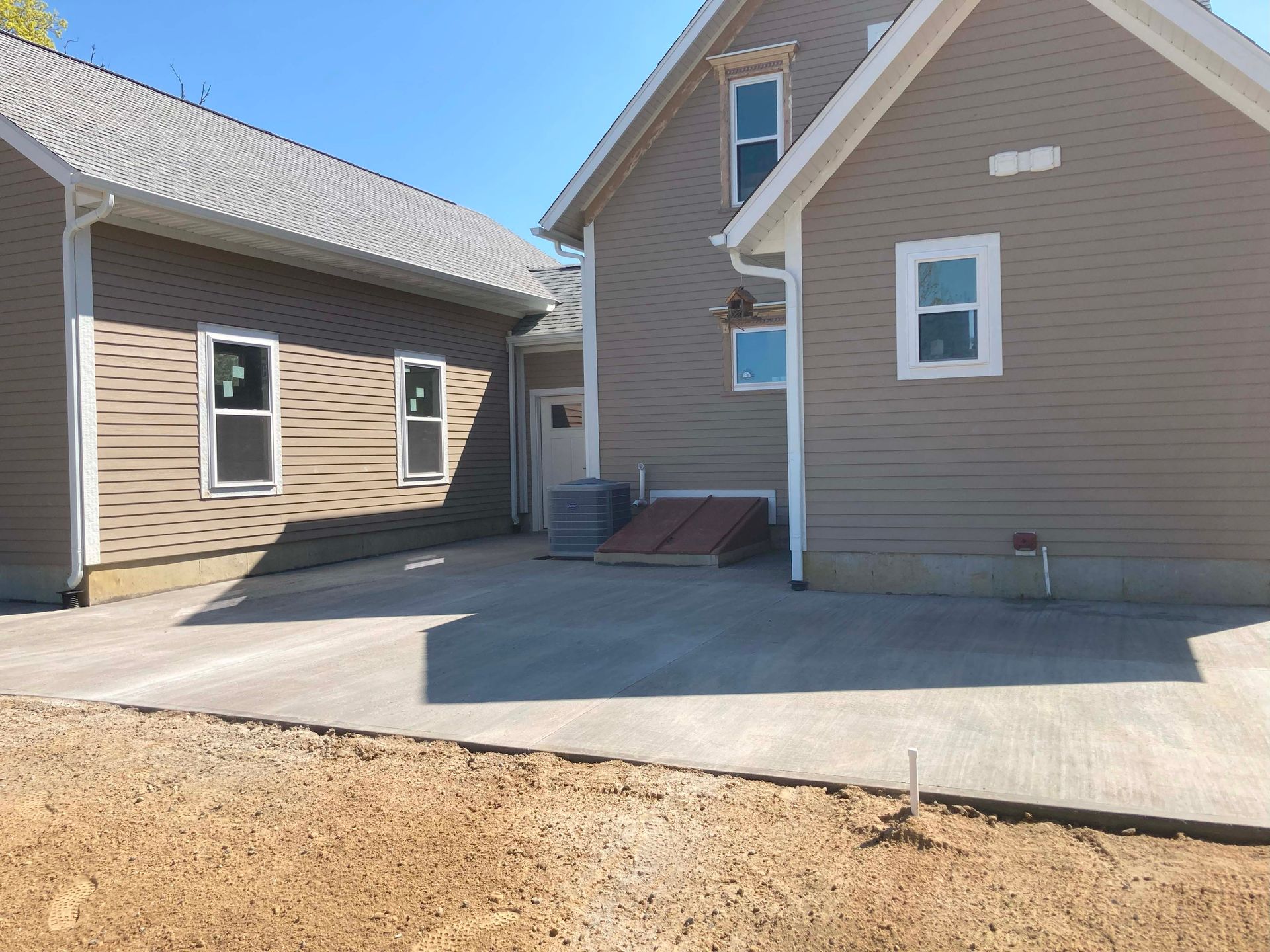 Buildings with tan siding and a concrete driveway.