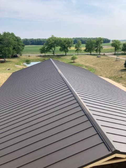 Dark metal roof with a central ridge, overlooking a rural landscape.