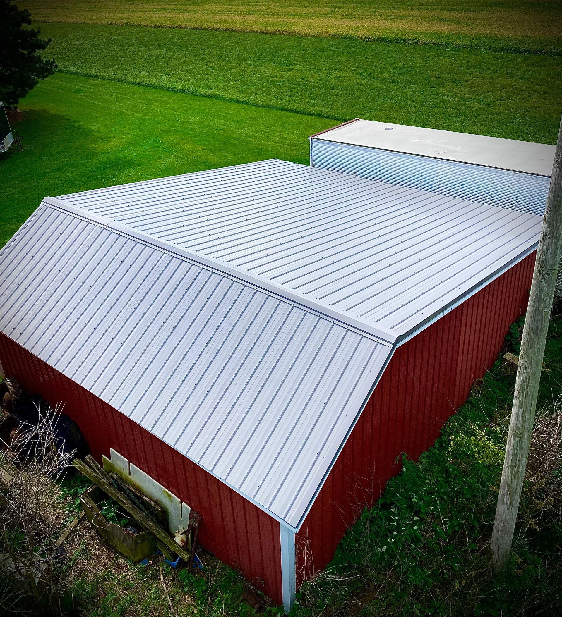 Red barn with a silver metal roof, set in a green field.