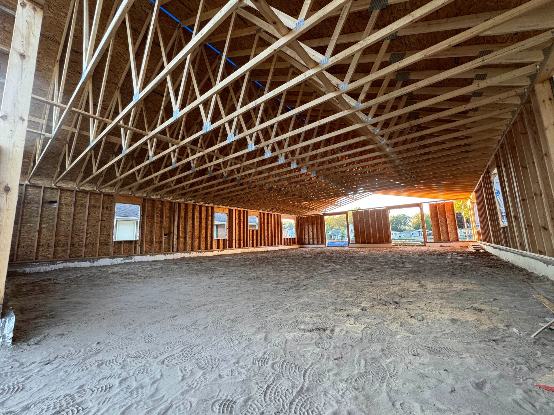 Unfinished building interior with wood framing, dirt floor, and natural light streaming in from the open doorway.