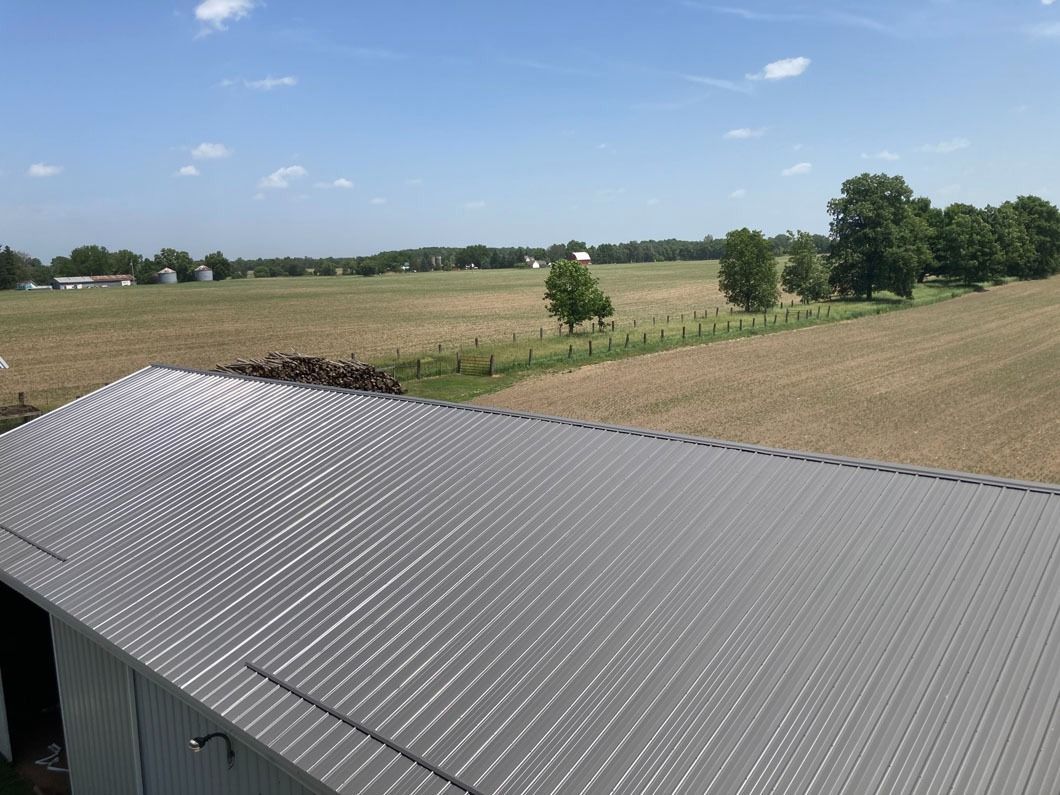 Metal roof with field view under blue sky.