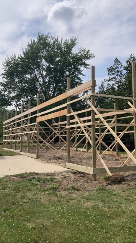 Wooden frame of a barn under construction, set outdoors on a grassy lot.