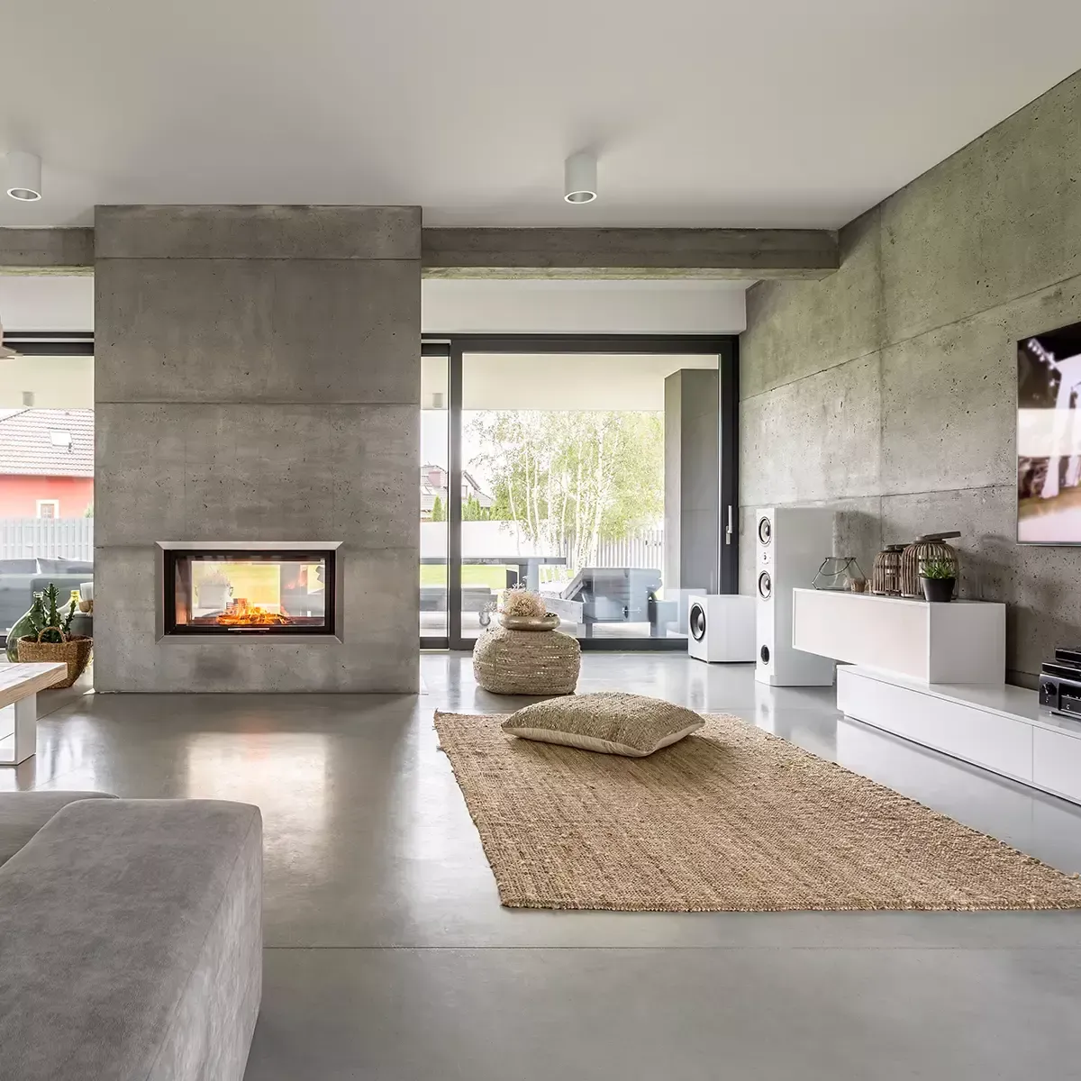 Soggiorno moderno con una grande finestra con vista sugli alberi, un divano dai colori chiari e un tavolino da caffè minimalista.