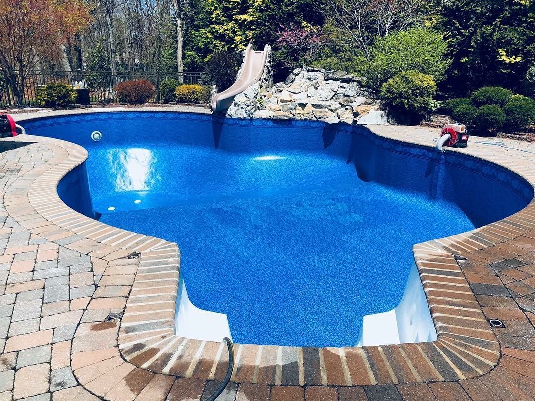 A large blue swimming pool with a slide in the backyard.