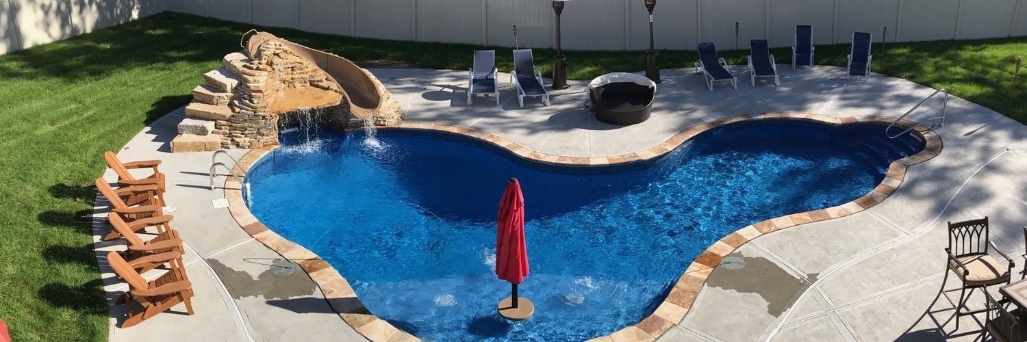 An aerial view of a heart shaped swimming pool with a red umbrella in the middle.