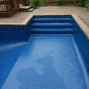 A blue swimming pool with stairs leading up to it.