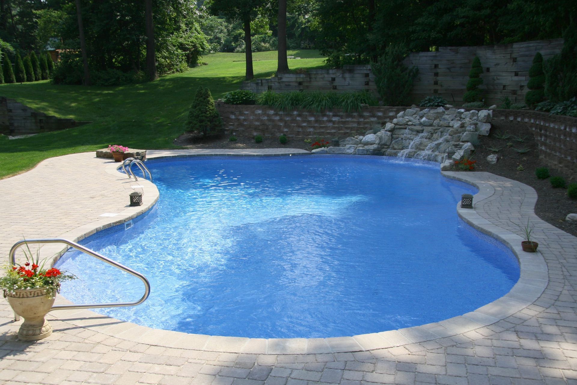 A large blue swimming pool is surrounded by a brick patio.