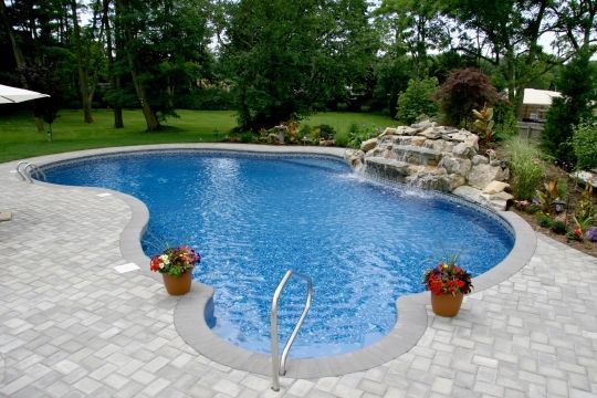 A large swimming pool with a waterfall in the backyard.
