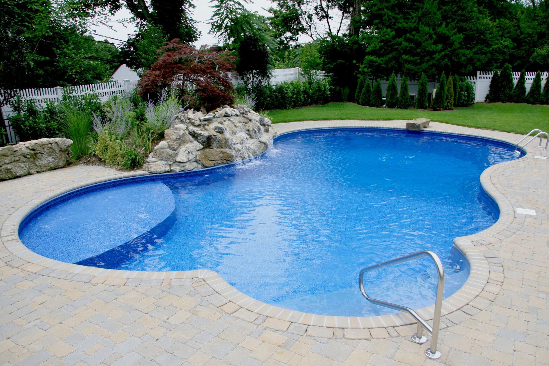 A large swimming pool with a waterfall in the backyard