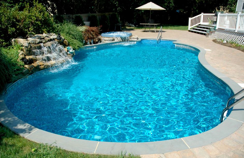 A large swimming pool with a waterfall in the backyard