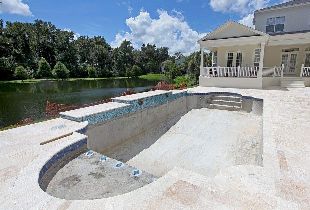 An empty swimming pool with a house in the background