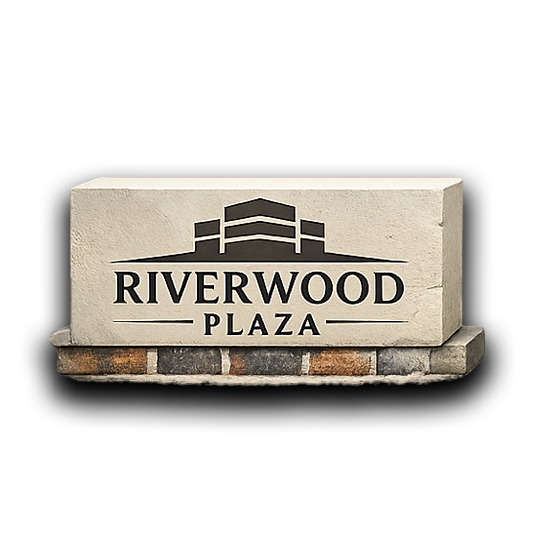 Riverwood Plaza sign on brick base; beige stone with dark logo, black text.