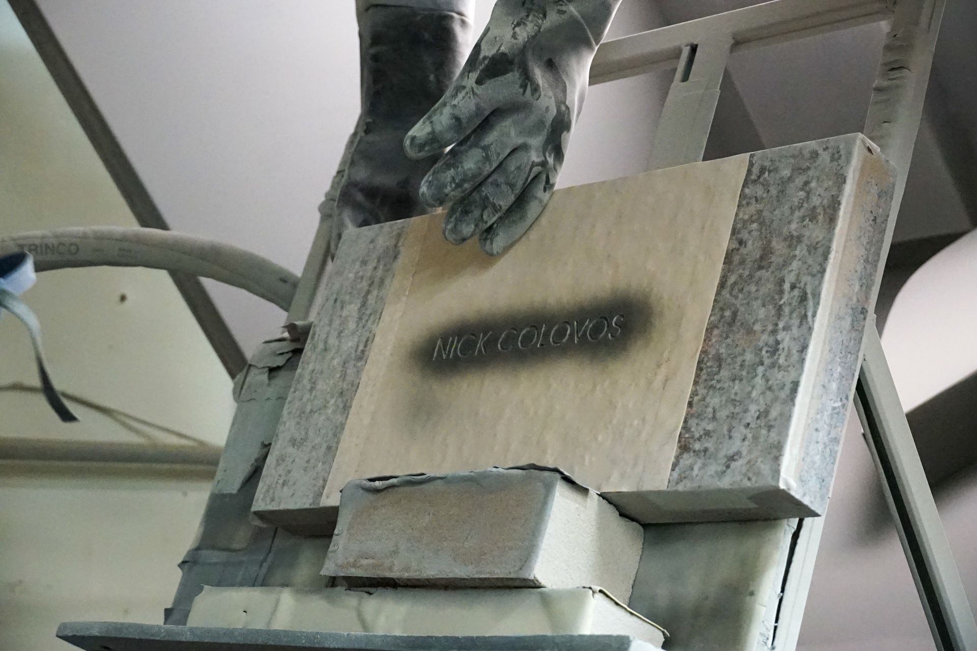 A person in gloves spraying stencil lettering 