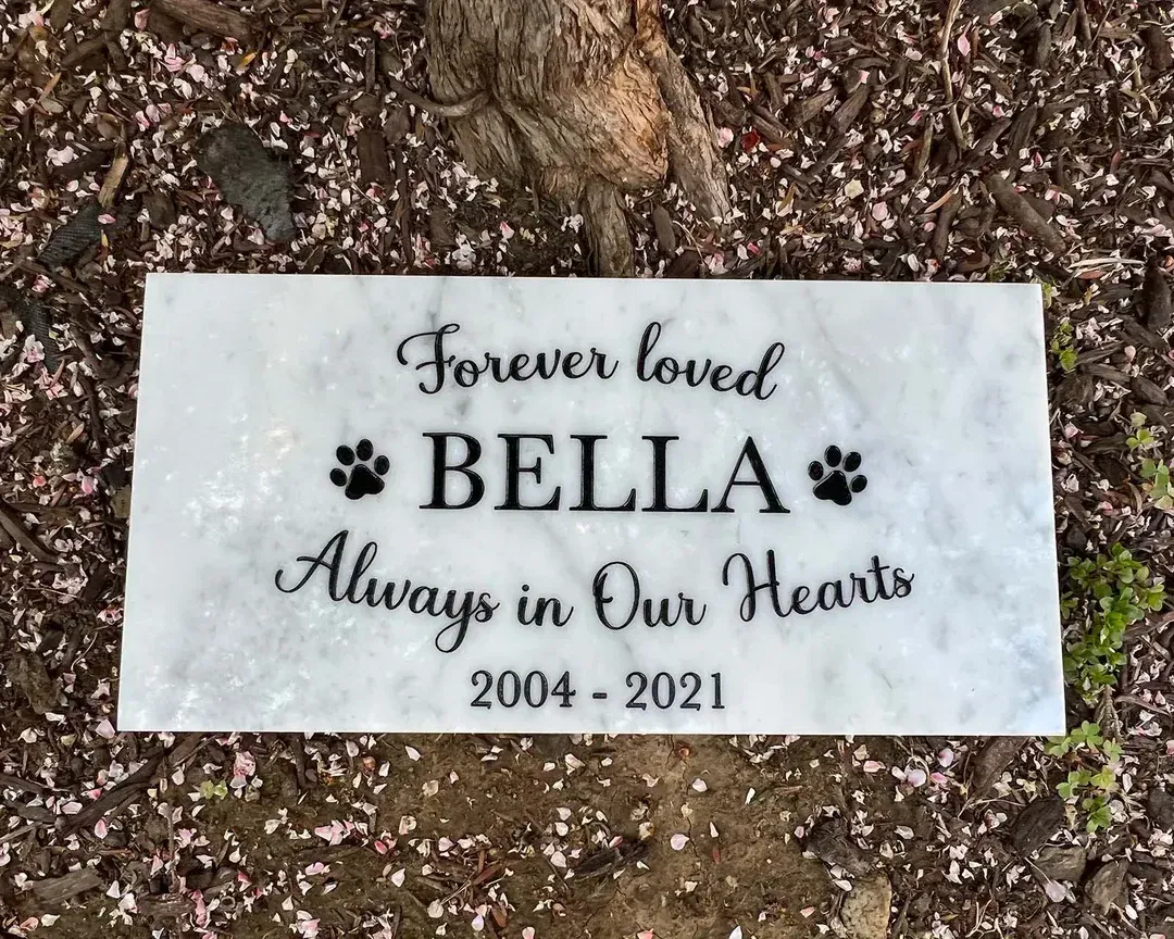 Marble pet memorial for Bella, with paw prints, dates 2004-2021, and inscription 