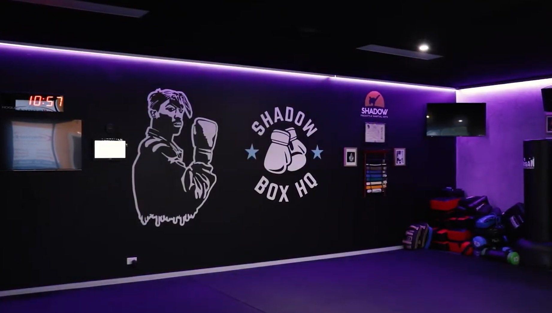 A gym with purple lights and a shadow box logo on the wall.