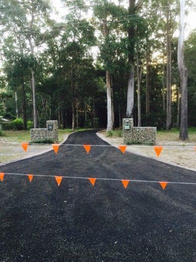 An Asphalt Driveway With Orange Flags Going Across It— Territory Bitumen Services In Tivendale, NT