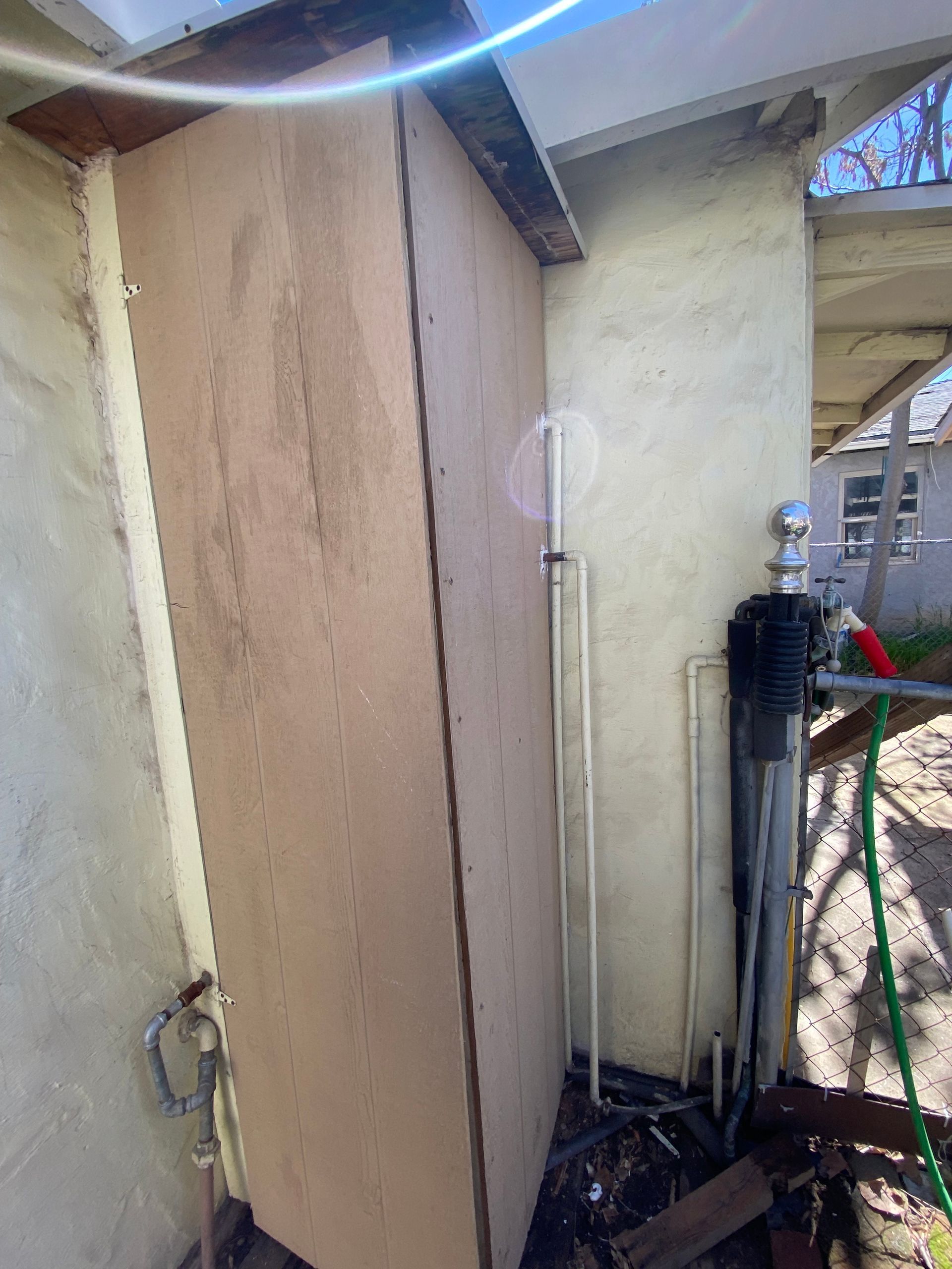 A shed with a hose attached to the side of it.