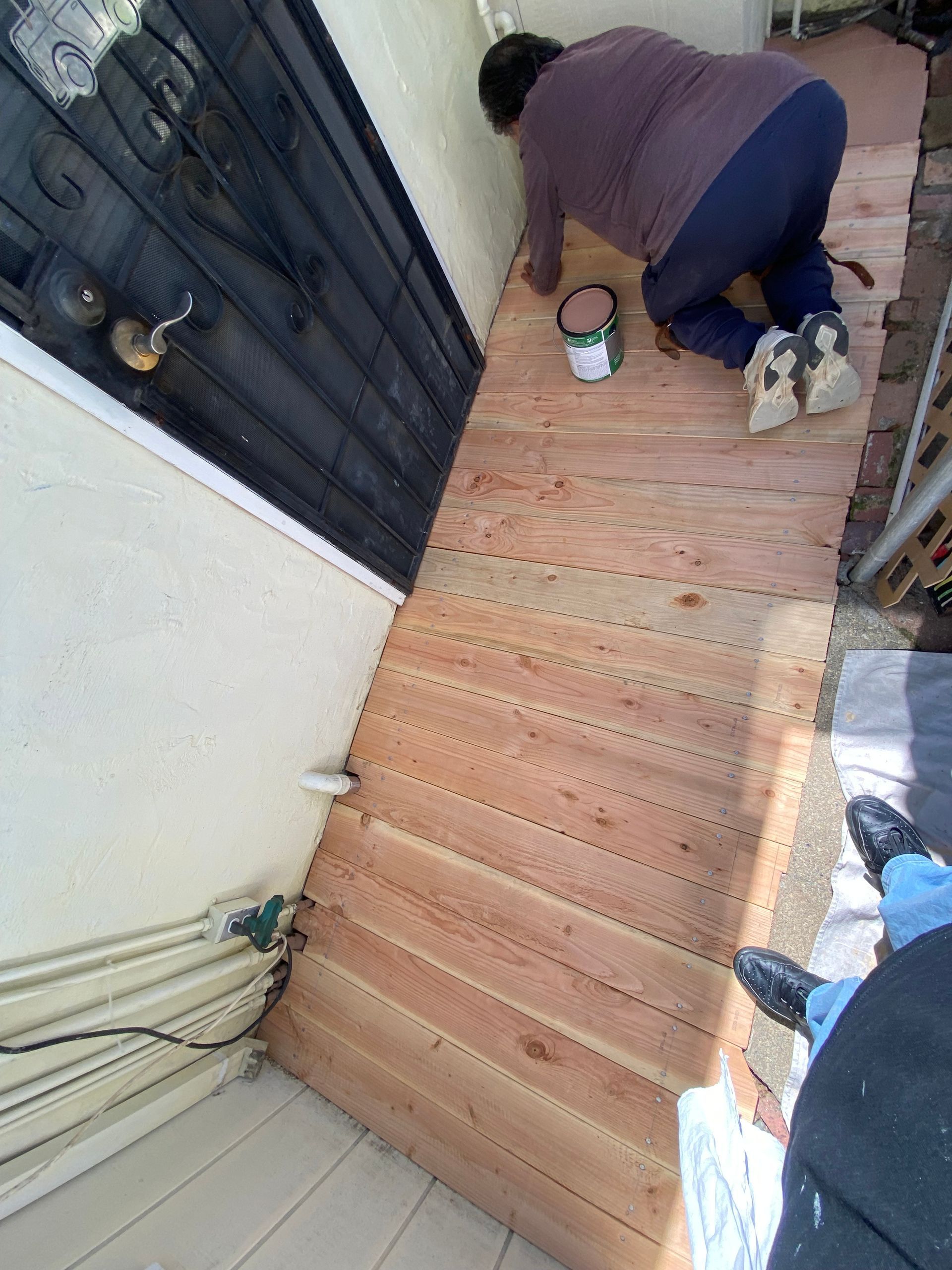A woman is kneeling on a wooden floor in front of a door.