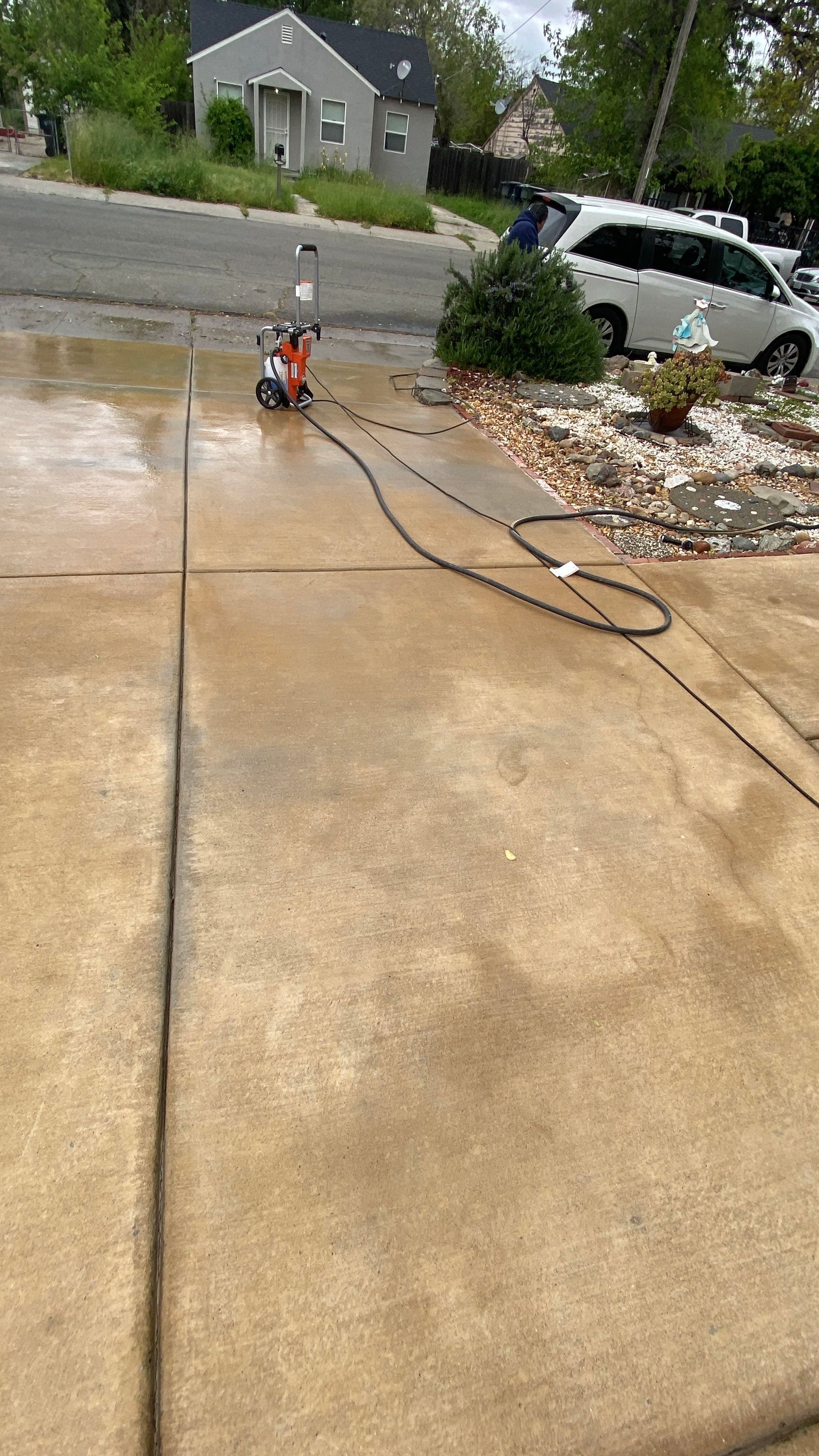 A person is using a pressure washer to clean a driveway.