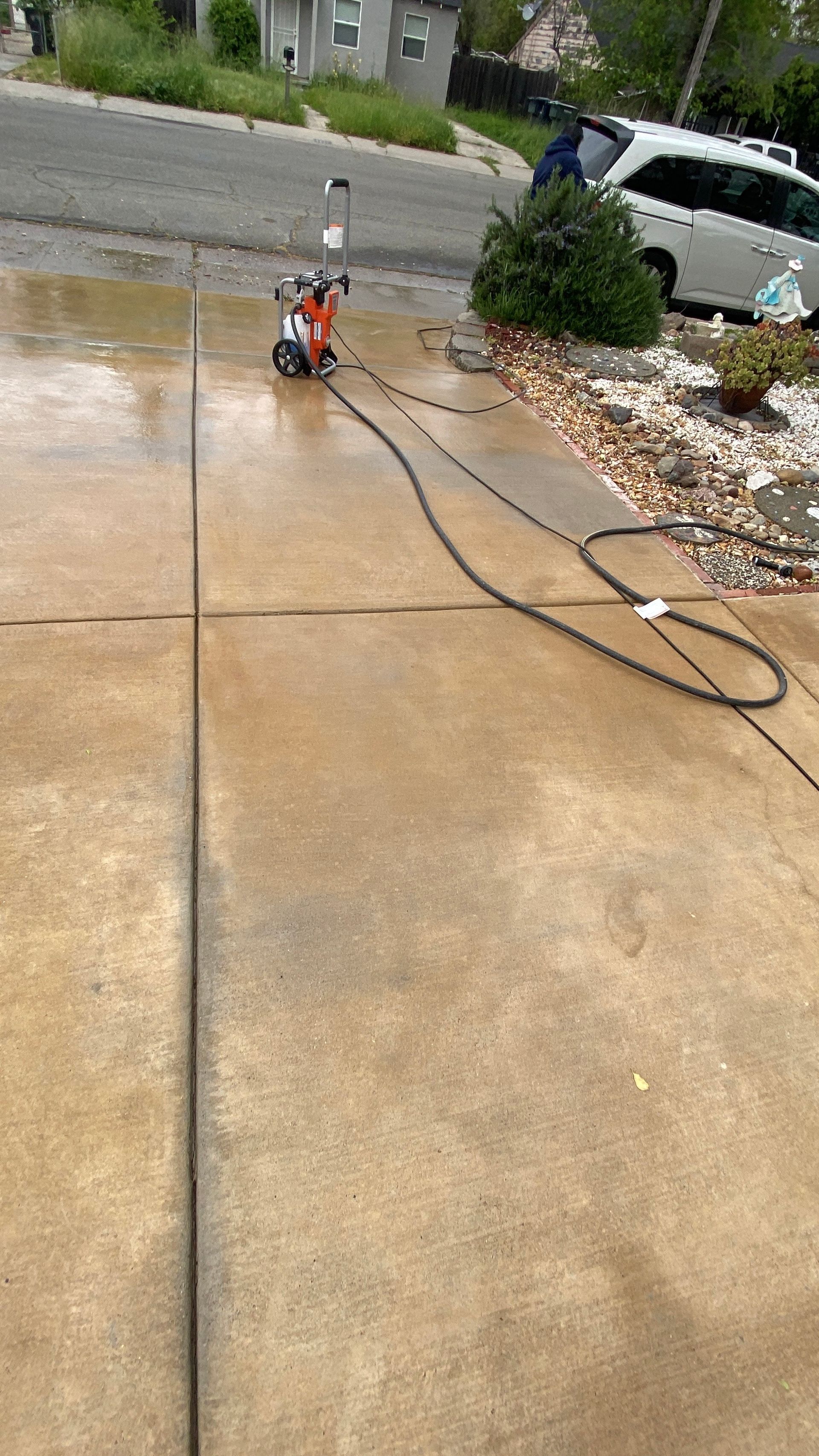 A pressure washer is being used to clean a driveway.
