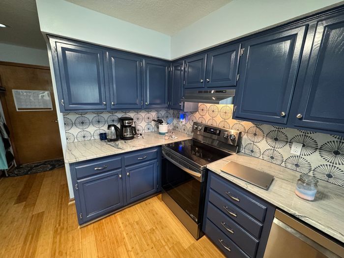 A kitchen with oak cabinets that were painted indigo batik, with a modern backsplash