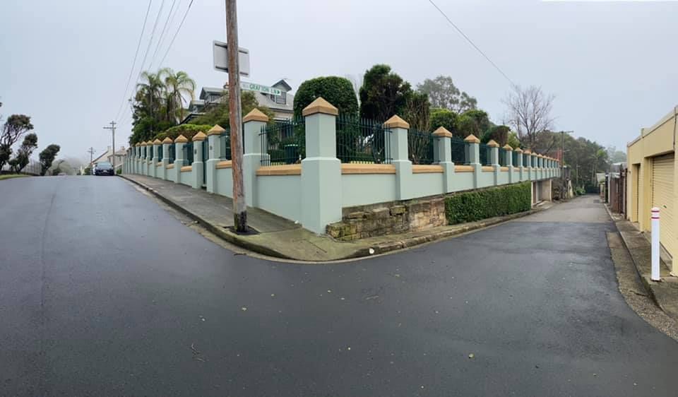 A pale green wall with pillars surrounds a large house on a foggy street corner. — S D Maintenance In Point Clare, NSW