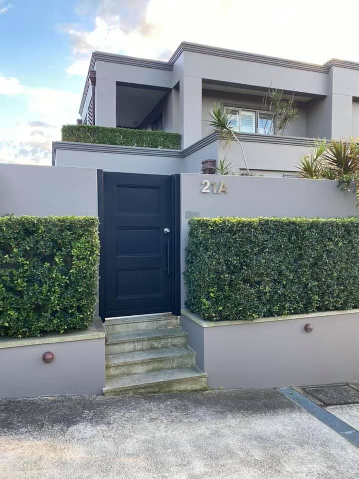 Black Gate in a Grey Wall With Hedges, Leading to a Modern Grey House — S D Maintenance In Erina, NSW
