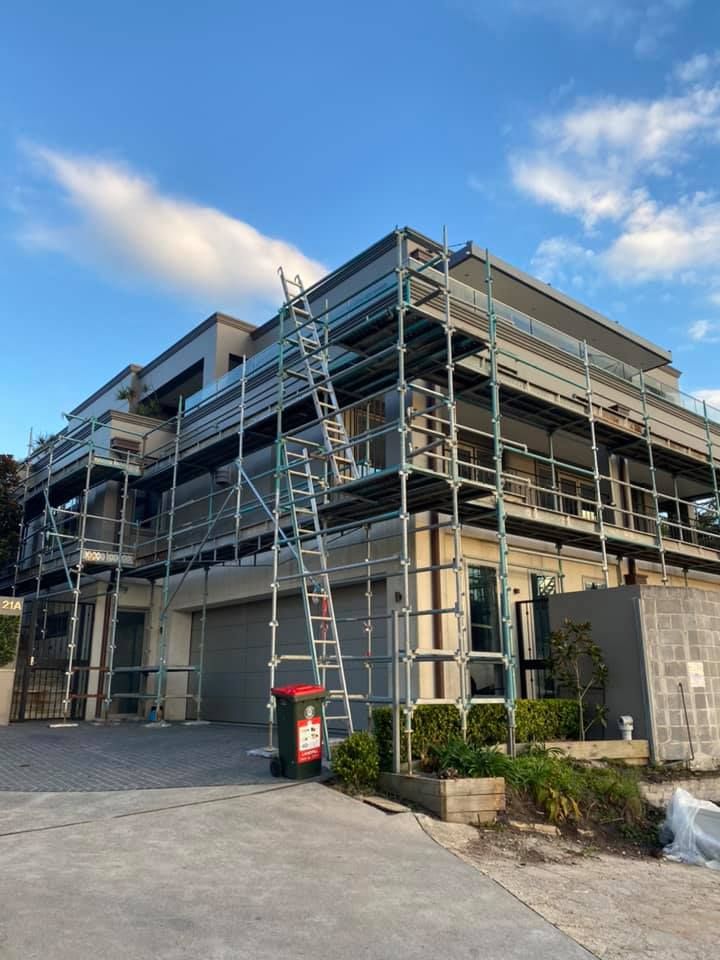 A house under renovation with scaffolding surrounding it. A ladder leans against the scaffolding; a blue sky above. — S D Maintenance In Point Clare, NSW