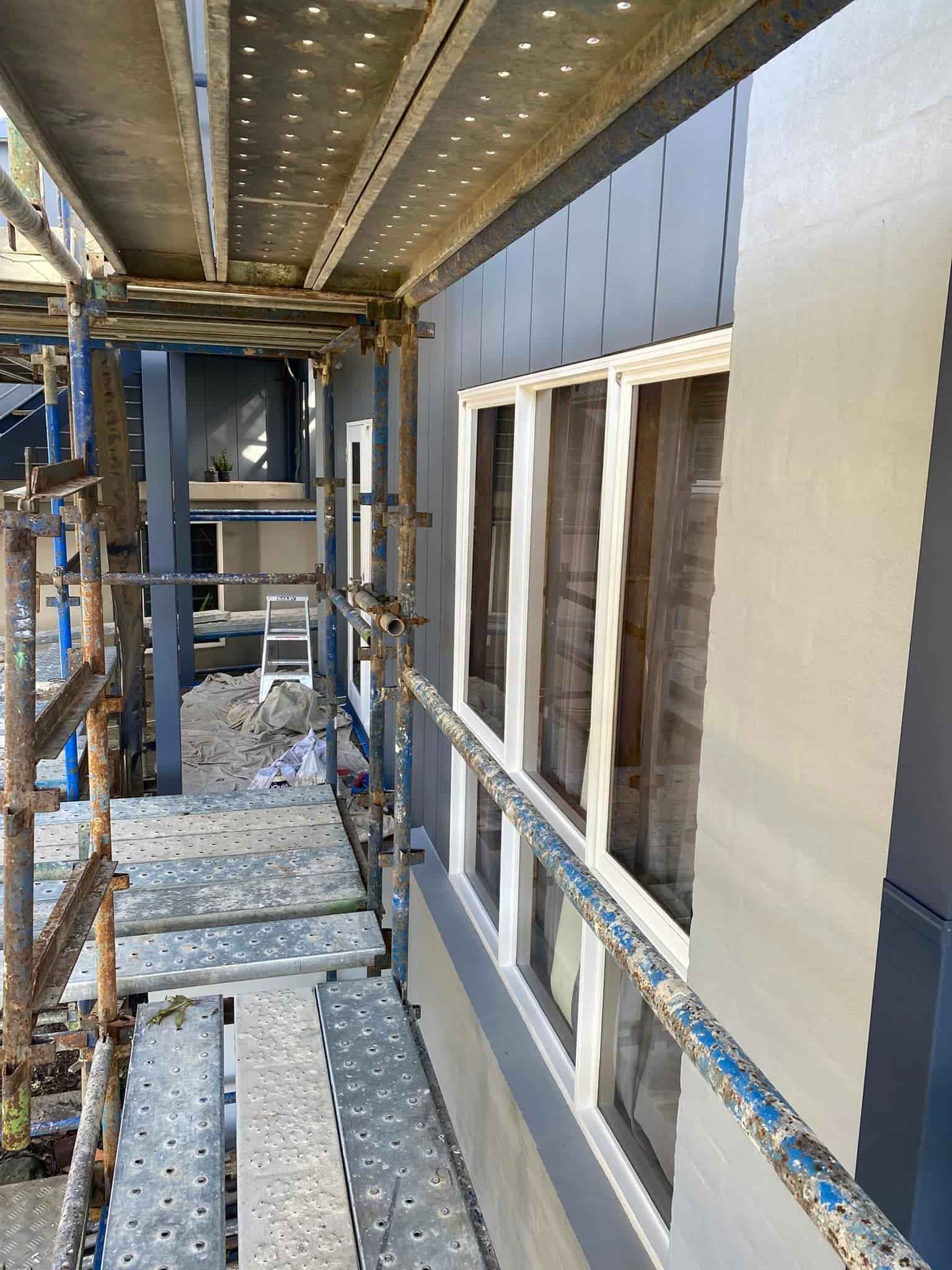 Scaffolding Alongside a Building With Gray Siding and White-framed Windows — S D Maintenance In Point Clare, NSW