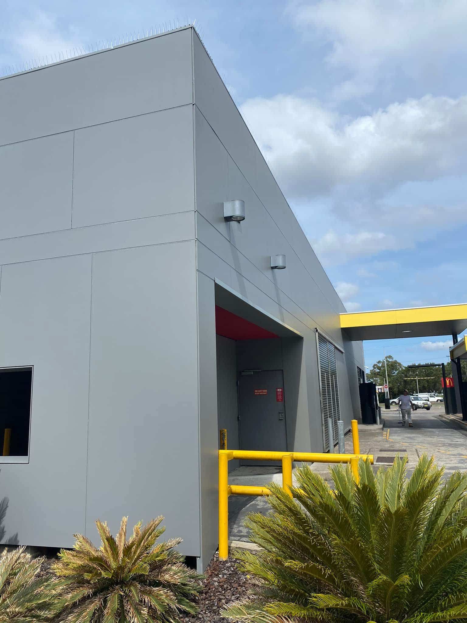 Gray Building With Yellow Accents. Drive-thru With Person — S D Maintenance In Kincumber, NSW