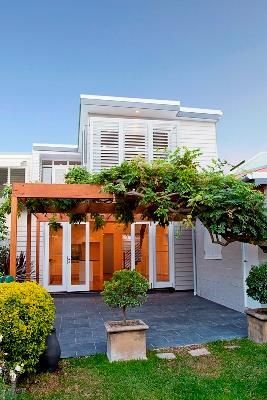 Two-Story White House With Wooden Pergola and Green Foliage — S D Maintenance In Point Clare, NSW