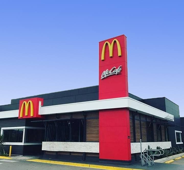 McDonald's restaurant building, red and black exterior, gold arches, McCafe sign, clear blue sky. — S D Maintenance In Point Clare, NSW