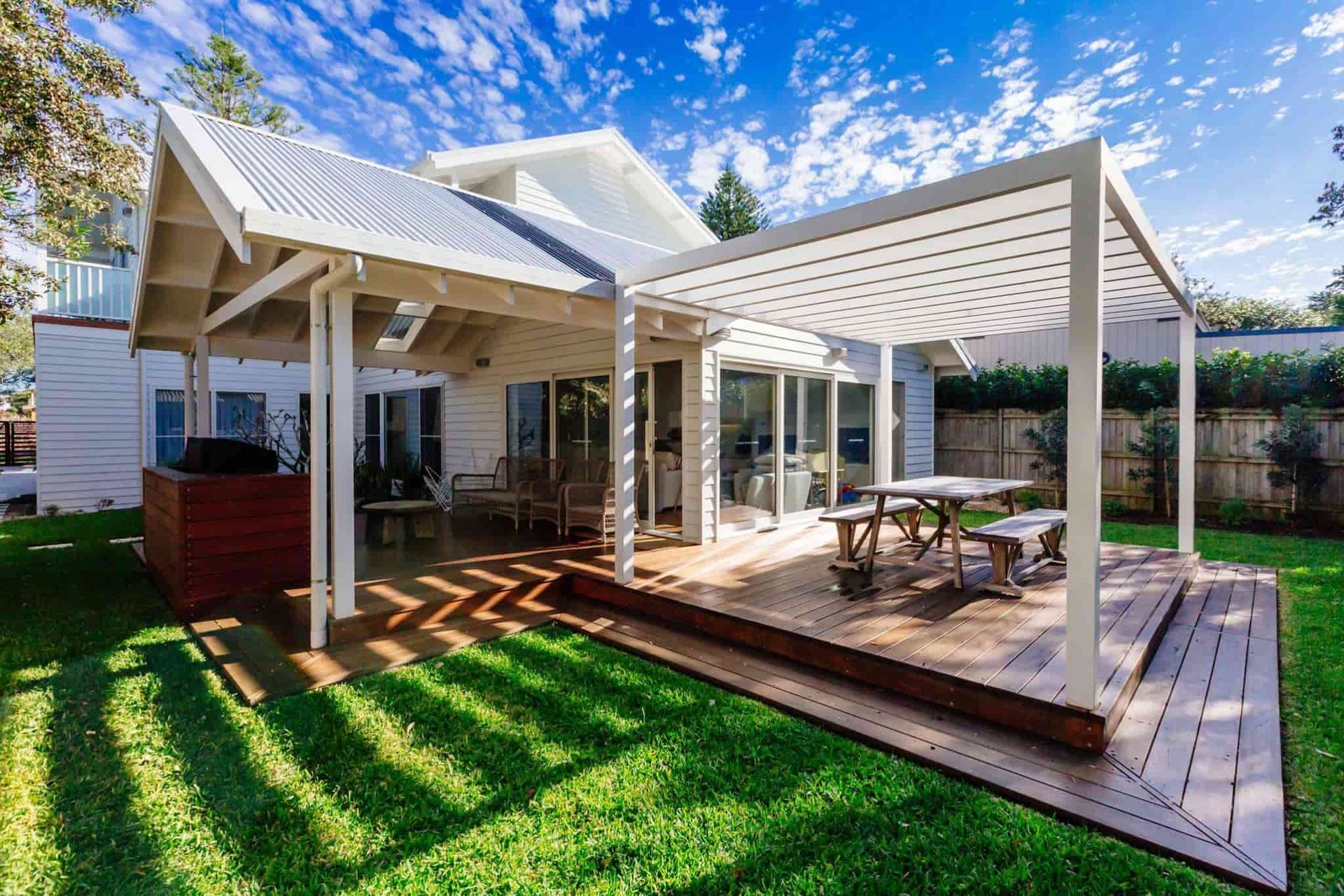 White House With Pergola and Wooden Deck on a Sunny Day With Green Grass — S D Maintenance In Terrigal, NSW