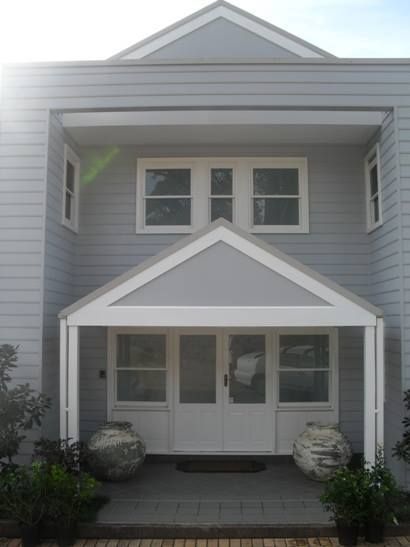 Gray house with white trim, covered entryway, and two urns flanking the door. — S D Maintenance In Point Clare, NSW