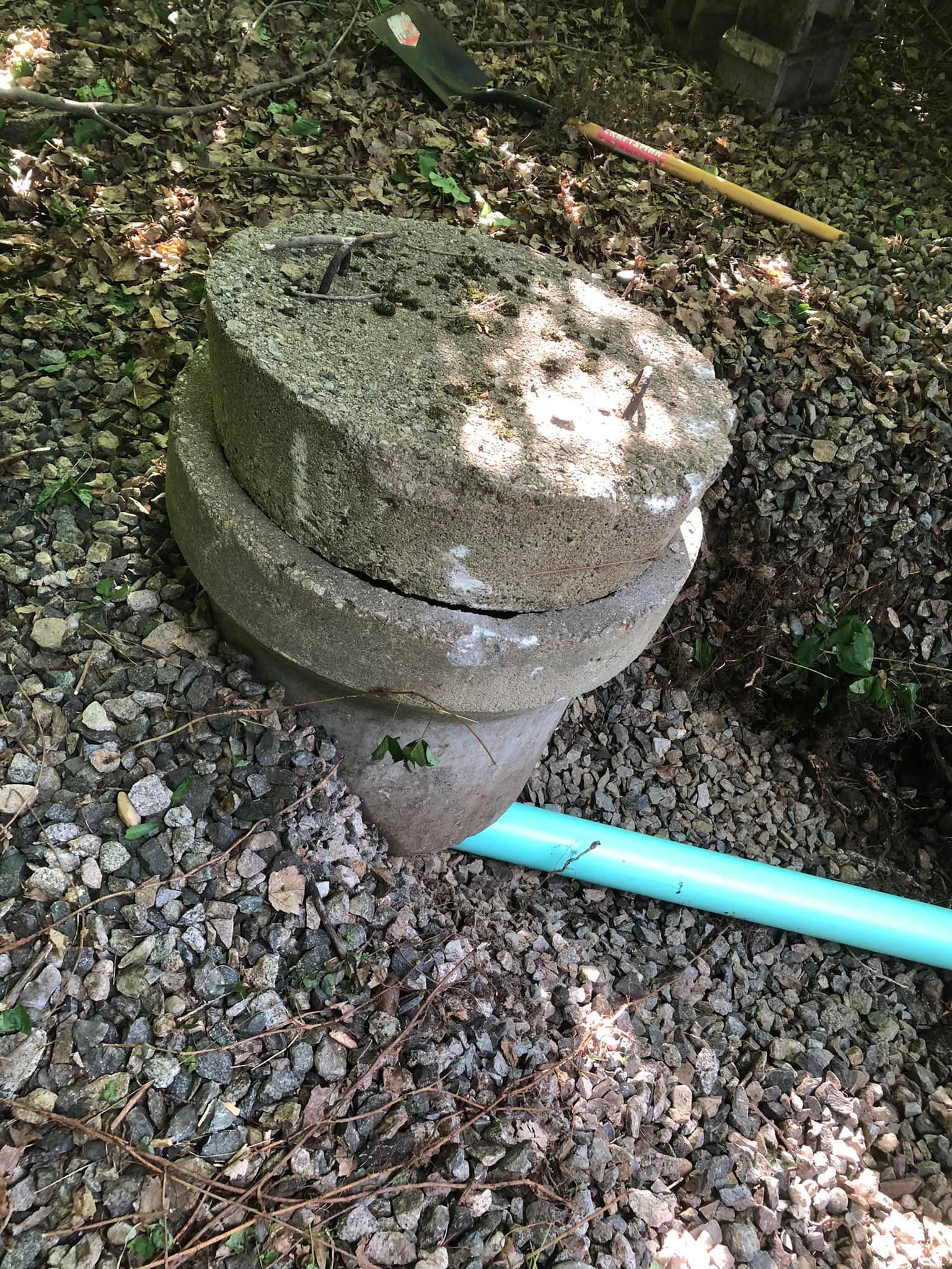 A concrete block is sitting on top of a pile of gravel next to a blue pipe.
