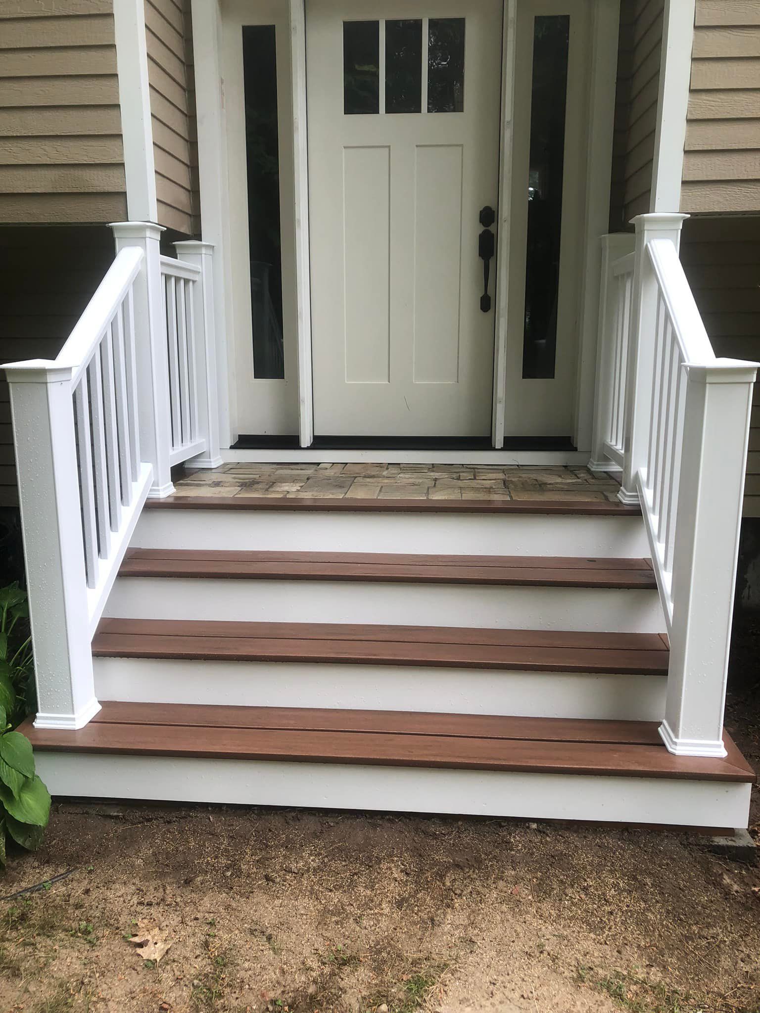 The front door of a house with wooden steps and a white railing.