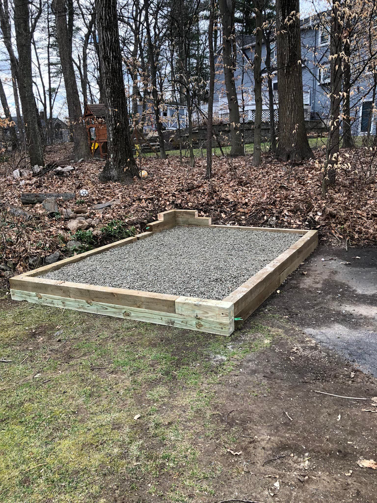 A wooden box filled with gravel is sitting on top of a lush green field.